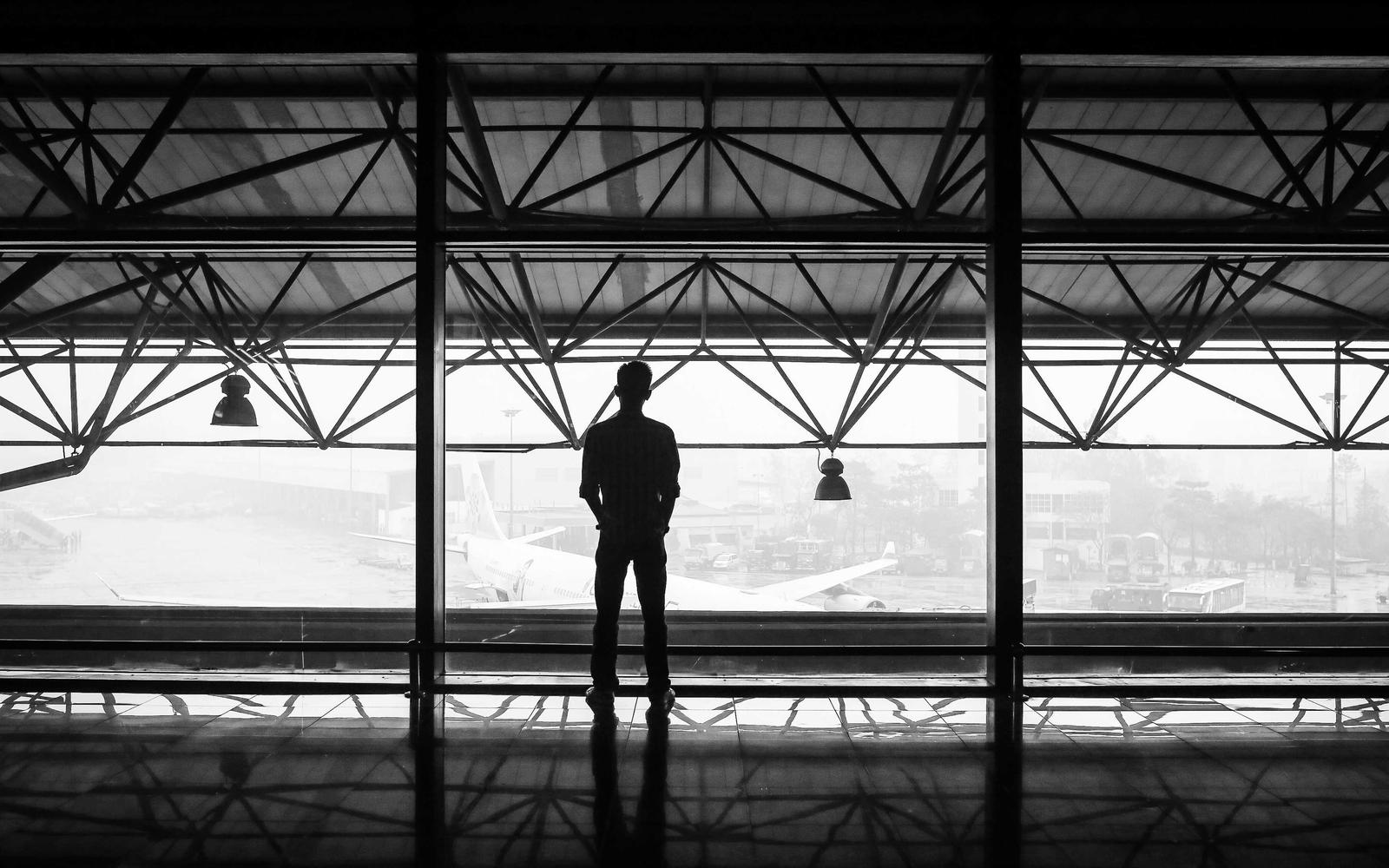 A person standing under a steel roof frame